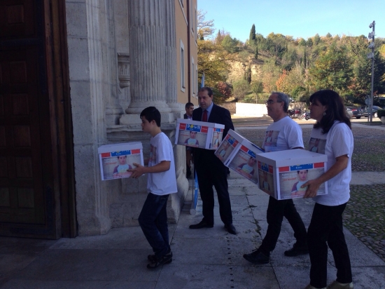 La familia, acompañada del gerente de DOWN ESPAÑA, Agustín Matía, llevan las cajas con las firmas. 